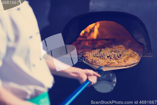 Image of chef removing hot pizza from stove