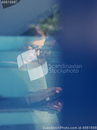 Image of Woman using tablet at home by the window