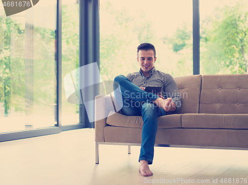 Image of man on sofa using tablet computer