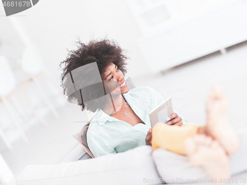 Image of african american woman at home using digital tablet