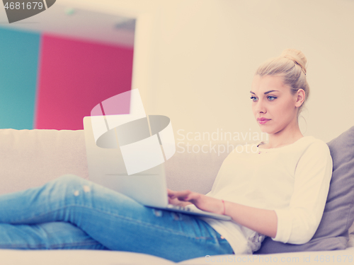 Image of Young woman using laptop at home