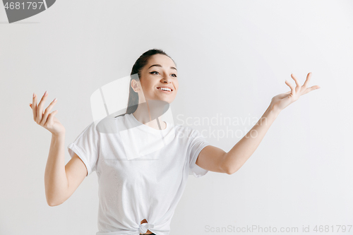 Image of The happy woman standing and smiling against gray background.