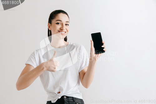 Image of Portrait of a confident casual girl showing blank screen of mobile phone