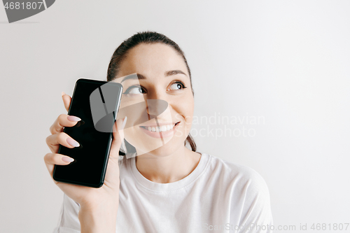 Image of Portrait of a confident casual girl showing blank screen of mobile phone