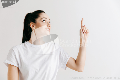Image of The happy woman standing and smiling against gray background.