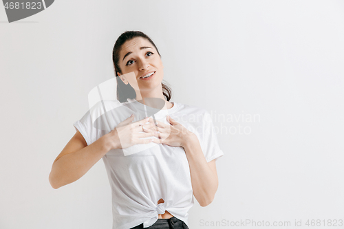 Image of The happy woman standing and smiling against gray background.