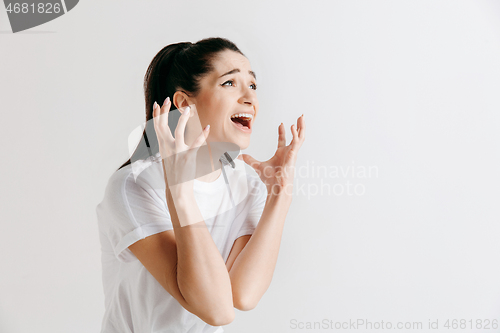 Image of The young emotional angry woman screaming on gray studio background