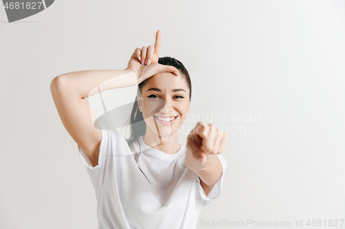 Image of Losers go home. Portrait of woman showing loser sign over forehead