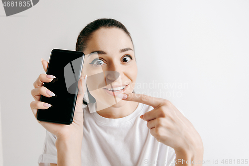 Image of Portrait of a confident casual girl showing blank screen of mobile phone