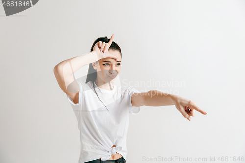 Image of Losers go home. Portrait of woman showing loser sign over forehead