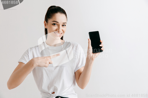 Image of Portrait of a confident casual girl showing blank screen of mobile phone