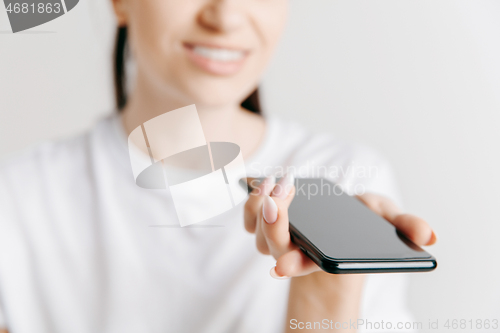 Image of Indoor portrait of attractive young woman holding blank smartphone