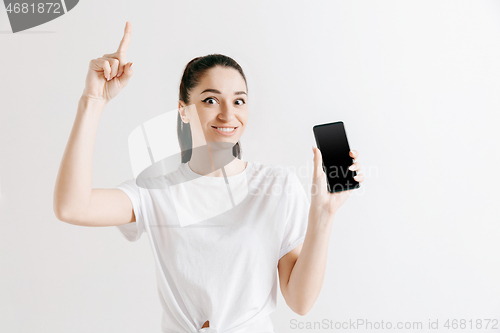 Image of Portrait of a confident casual girl showing blank screen of mobile phone