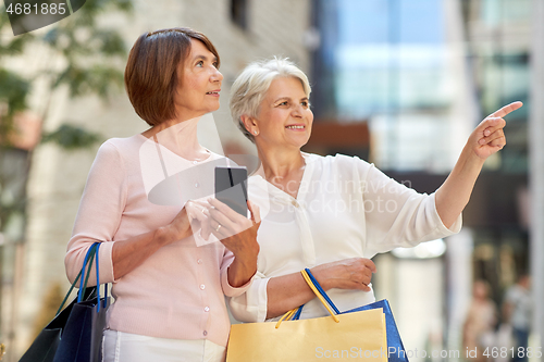 Image of old women with shopping bags and cellphone in city