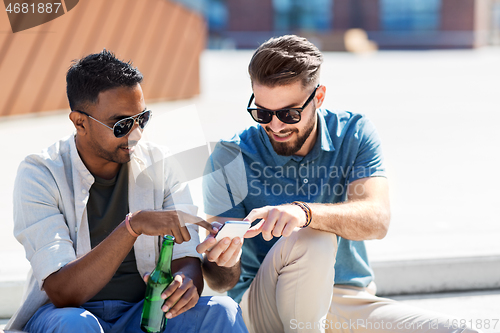 Image of men with smartphones drinking beer on street