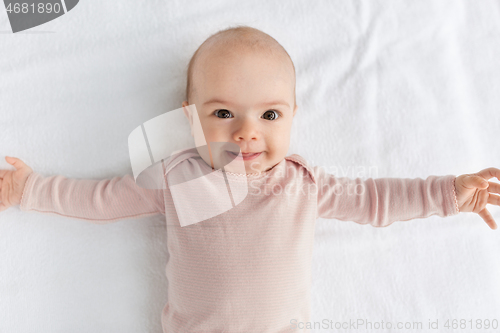 Image of sweet baby girl lying on white blanket