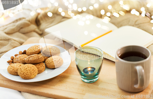 Image of cookies, tea and candle in holder at home