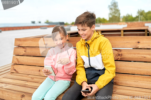 Image of children with smartphones sitting on street bench