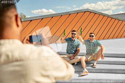 Image of man photographing friends drinking beer on street