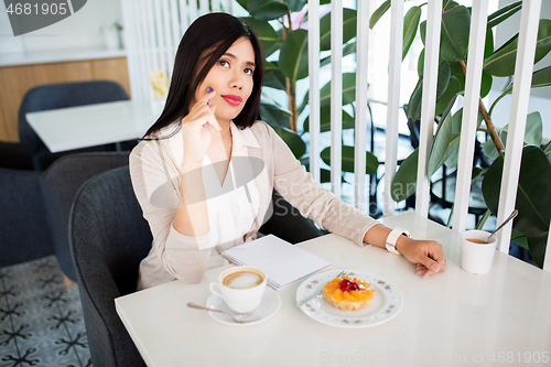 Image of asian woman with notebook and coffee at cafe