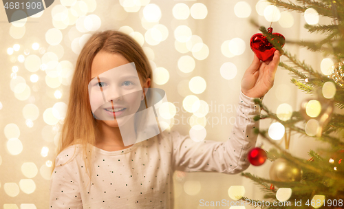 Image of happy girl in red dress decorating christmas tree