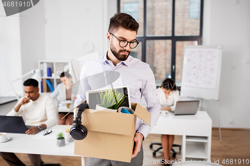 Image of sad fired male office worker with personal stuff