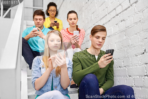 Image of students with smartphones sitting on stairs