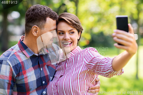 Image of happy couple in park taking selfie by smartphone