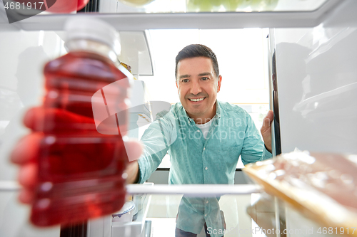 Image of man taking juice from fridge at home kitchen