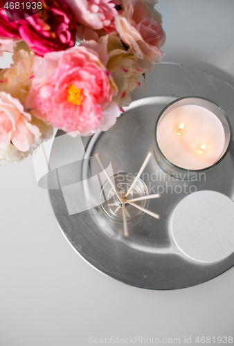 Image of aroma reed diffuser, candle and flowers on table