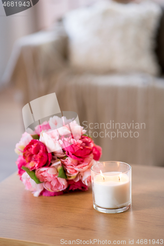 Image of burning fragrance candle and flower bunch at home