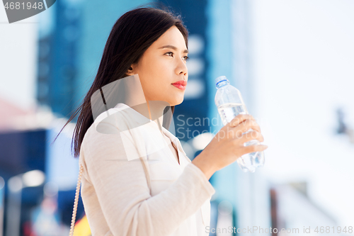 Image of asian woman drinking water from bottle in city