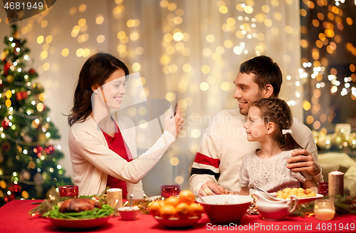 Image of happy family taking picture at christmas dinner