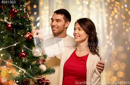 Image of happy couple decorating christmas tree at home