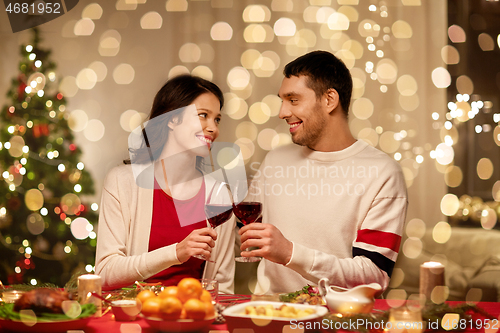 Image of happy couple drinking red wine at christmas dinner