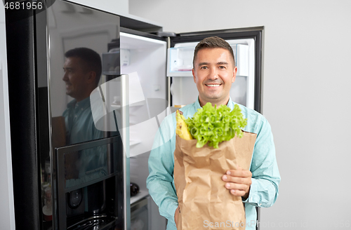 Image of man with new purchased food at home fridge