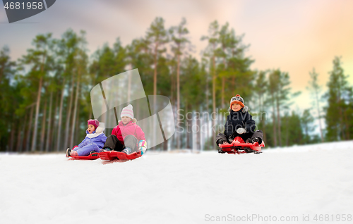 Image of kids sliding on sleds down snow hill in winter