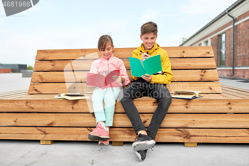 Image of school children with notebooks sitting on bench