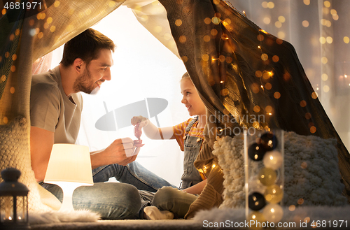 Image of family playing tea party in kids tent at home