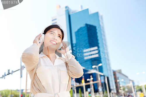 Image of happy smiling asian woman with headphones in city