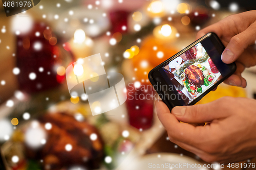 Image of hands photographing food at christmas dinner