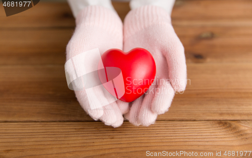 Image of hands in pink woollen gloves holding red heart