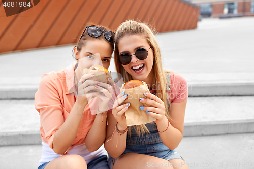 Image of teenage girls or friends eating burgers outdoors