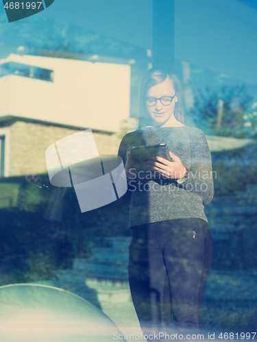 Image of Woman using tablet at home by the window