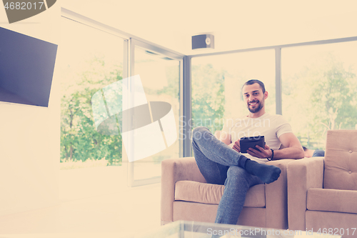 Image of young man using a tablet at home