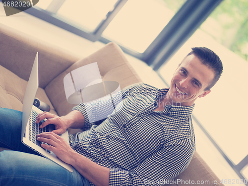 Image of Man using laptop in living room