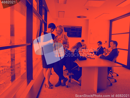 Image of Two Elegant Women Using Mobile Phone by window in office buildin