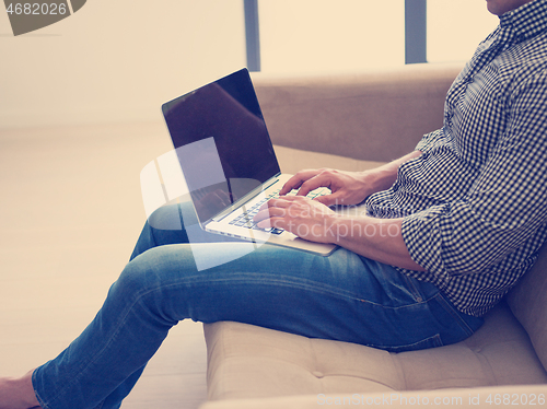 Image of Man using laptop in living room