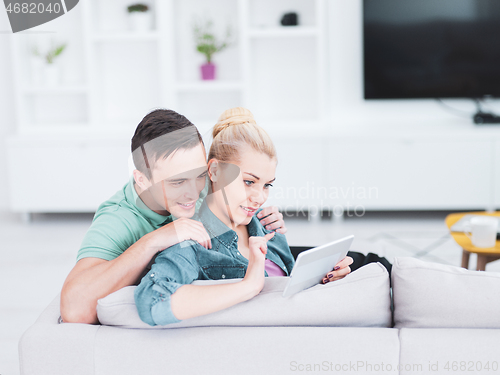 Image of couple relaxing at  home with tablet computers