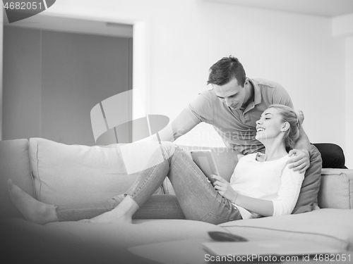 Image of couple relaxing at  home with tablet computers